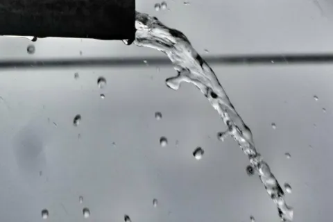 Water pouring out of the end of a black pipe